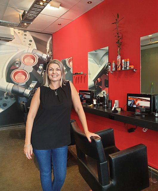 Photo of Emma standing by a hair cutting station in the salon